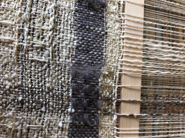 Close-up of a woven fabric featuring bold black and white stripes, showcasing texture and pattern details.