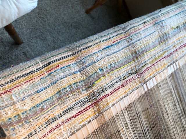 A close-up of a weaving loom showcasing a vibrant, colorful pattern in the fabric being created.