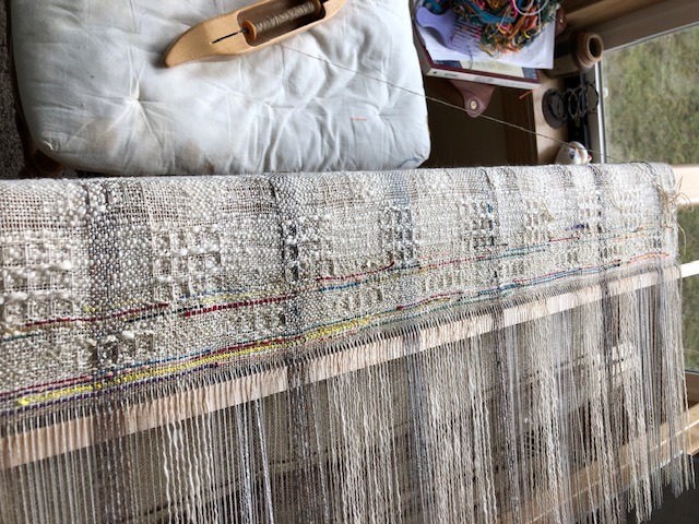 A weaving loom with a large piece of colorful fabric stretched across it, showcasing intricate patterns and textures.